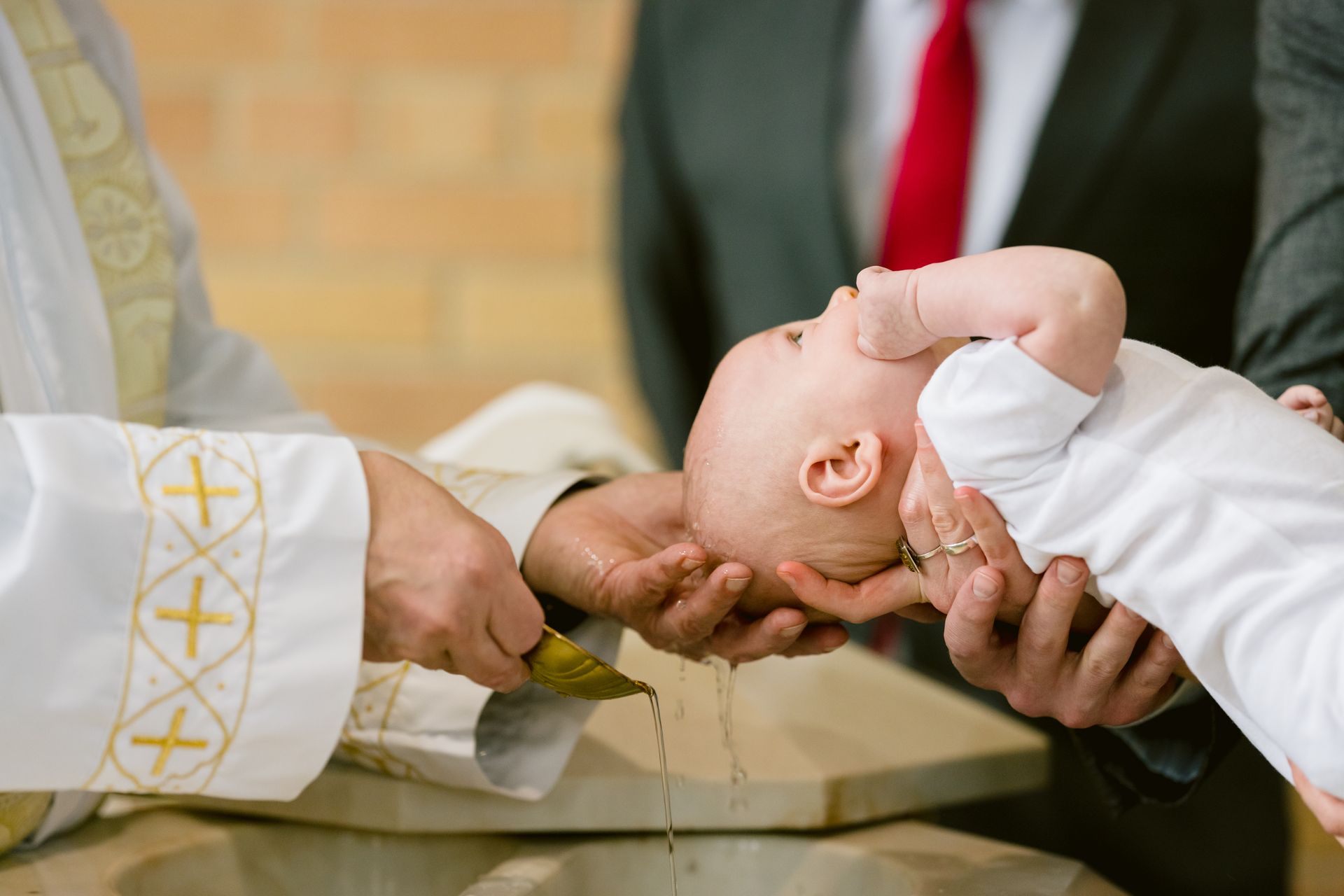A priest pours water over a baby’s head during a baptism ceremony.