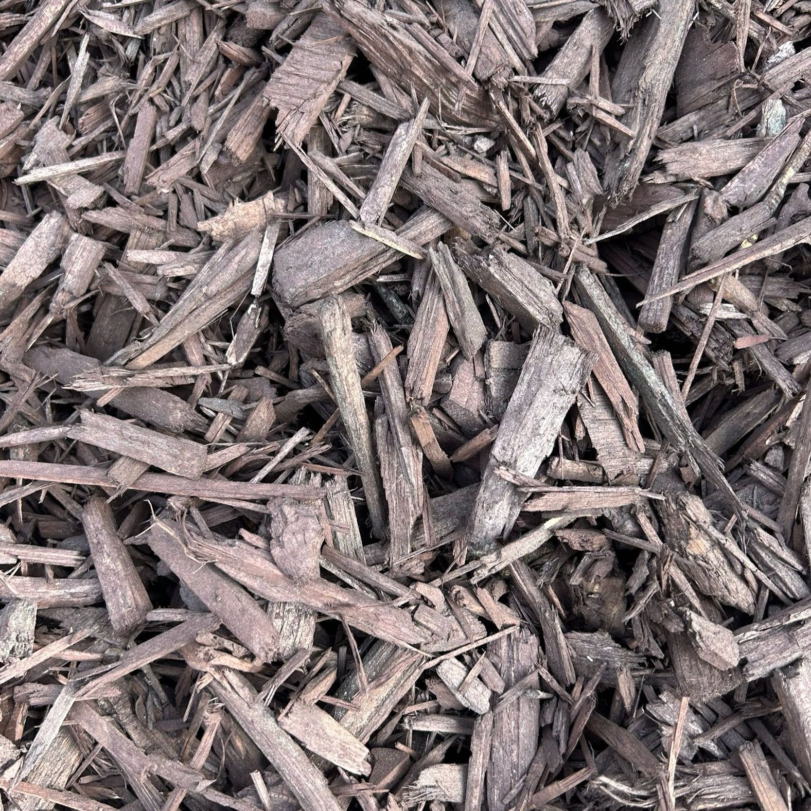 A pile of brown mulch is sitting on the ground.