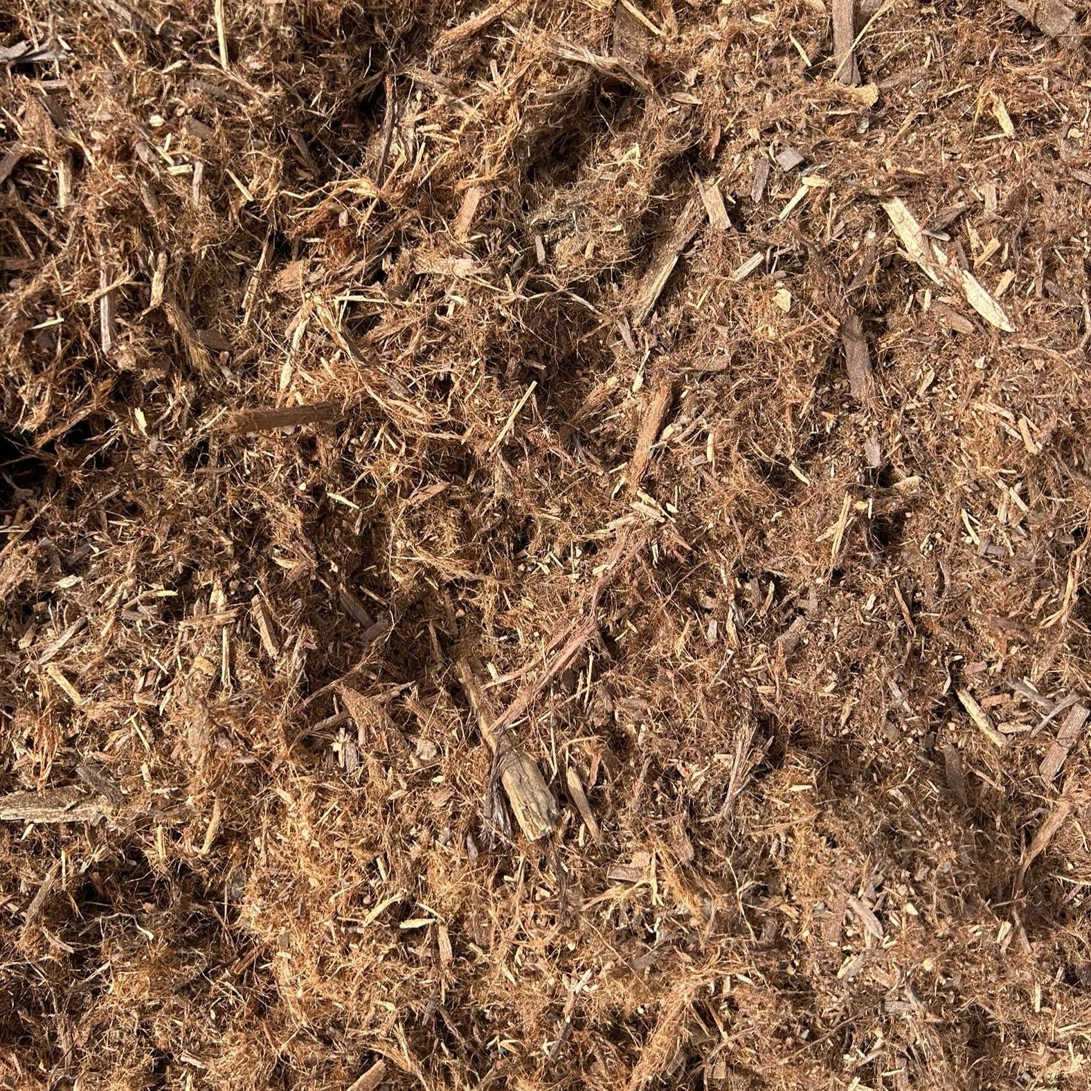 A pile of brown mulch is sitting on the ground.