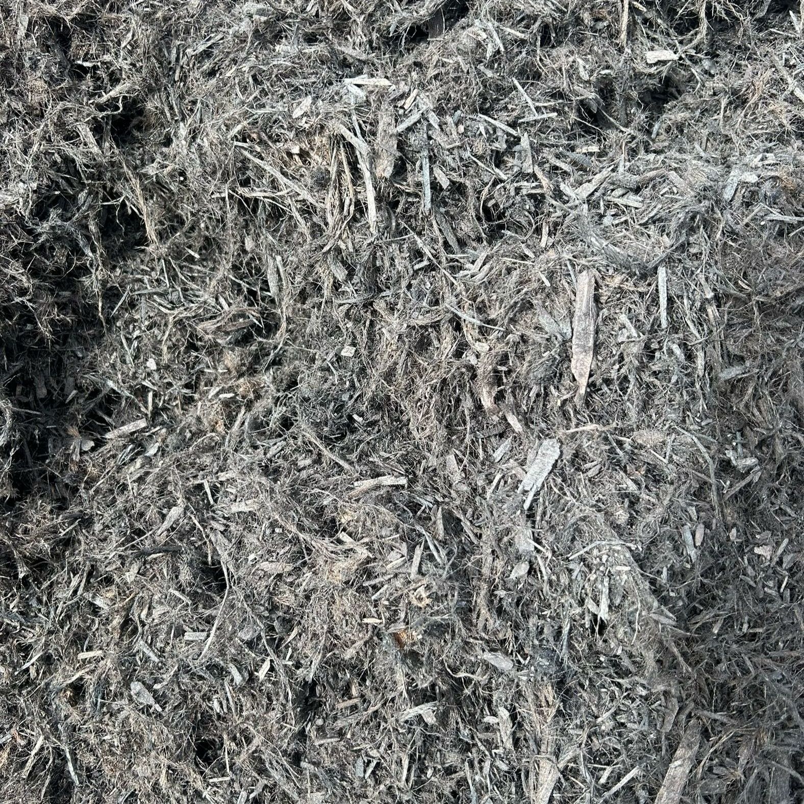 A pile of black mulch is sitting on the ground.