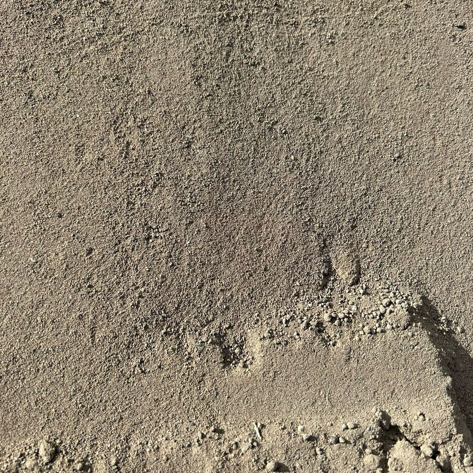 A close up of a pile of sand with a shadow on it.