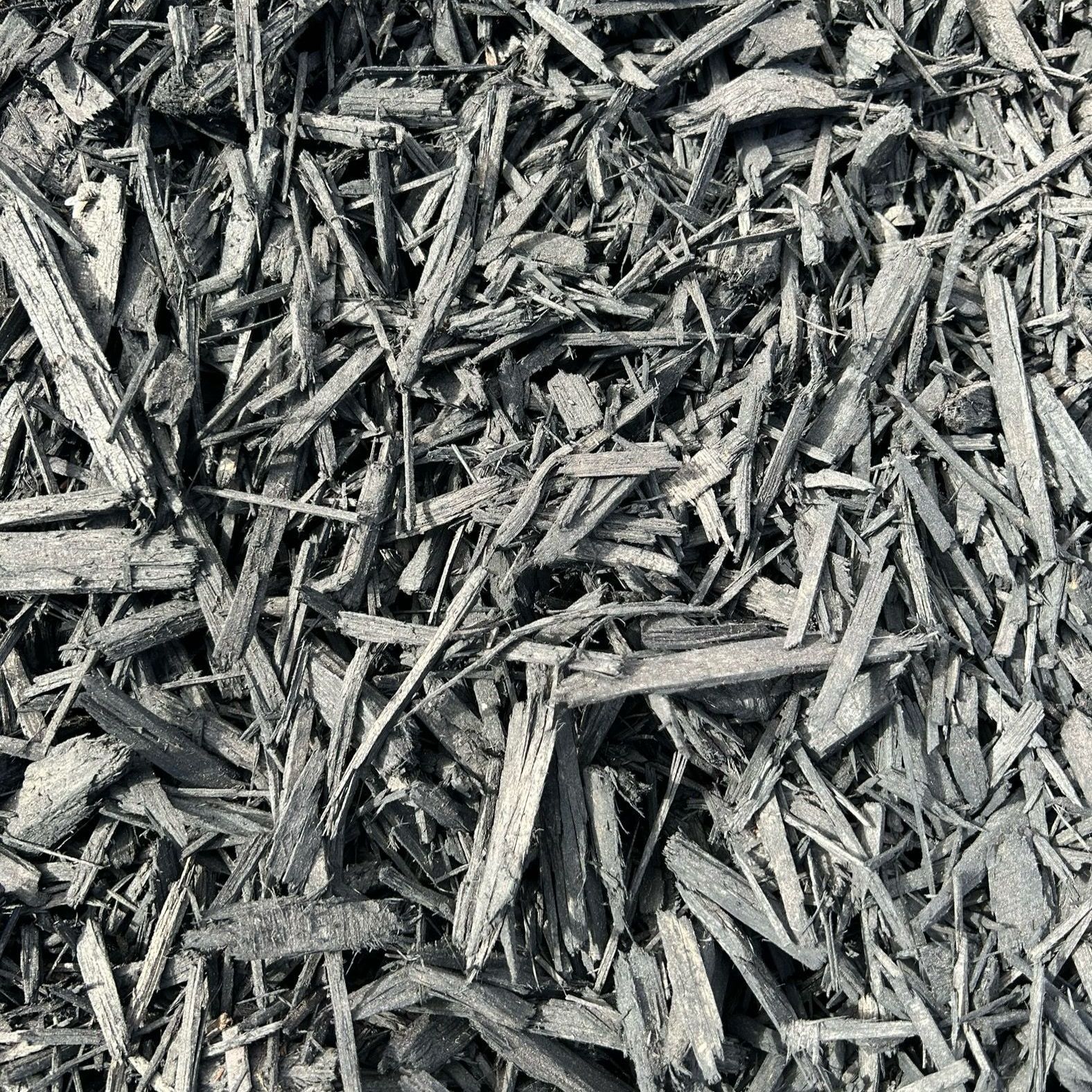 A pile of black mulch is shown in a black and white photo.