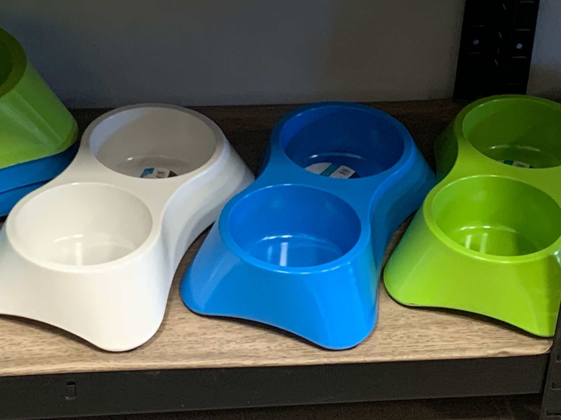 Tre ciotole per cani di colore diverso sono appoggiate su uno scaffale