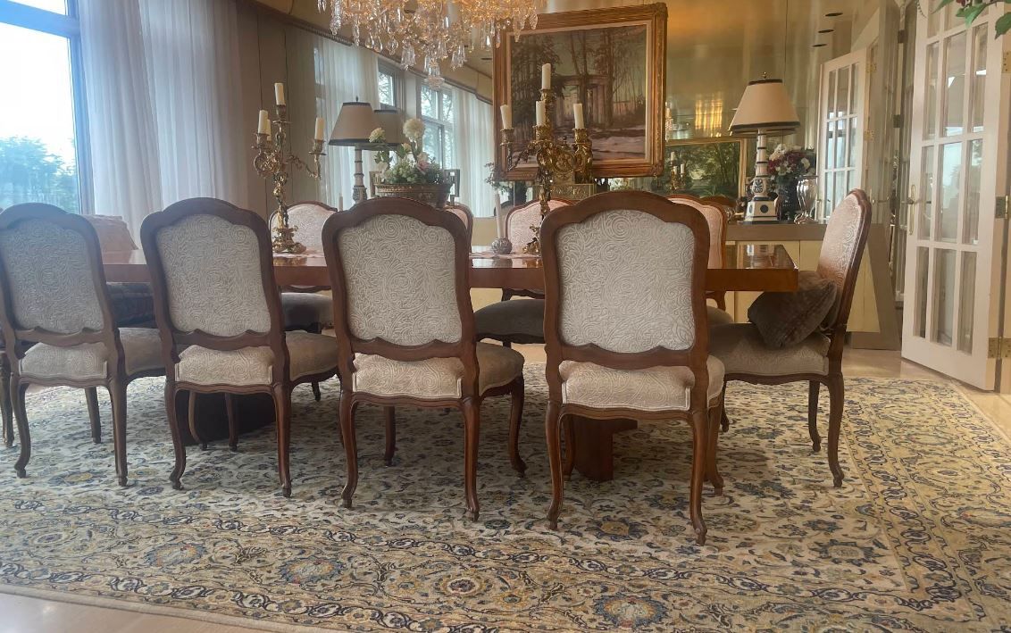 A dining room with a table and chairs and a rug.