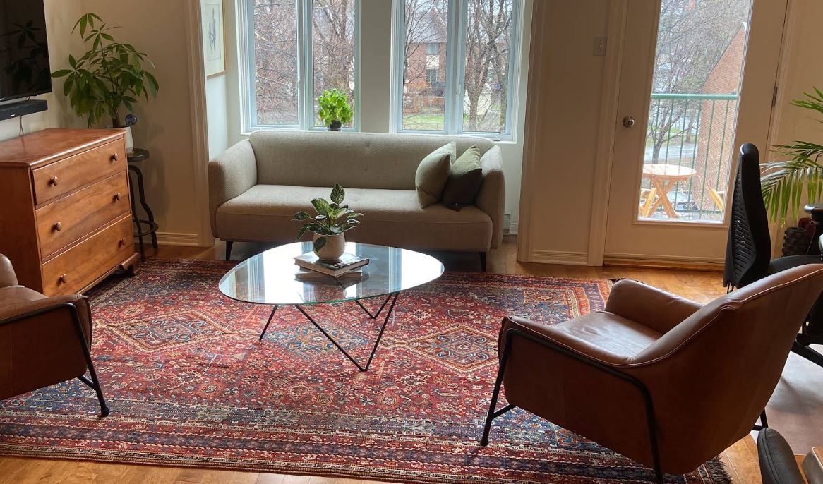 A living room with a couch , chairs , coffee table and rug.