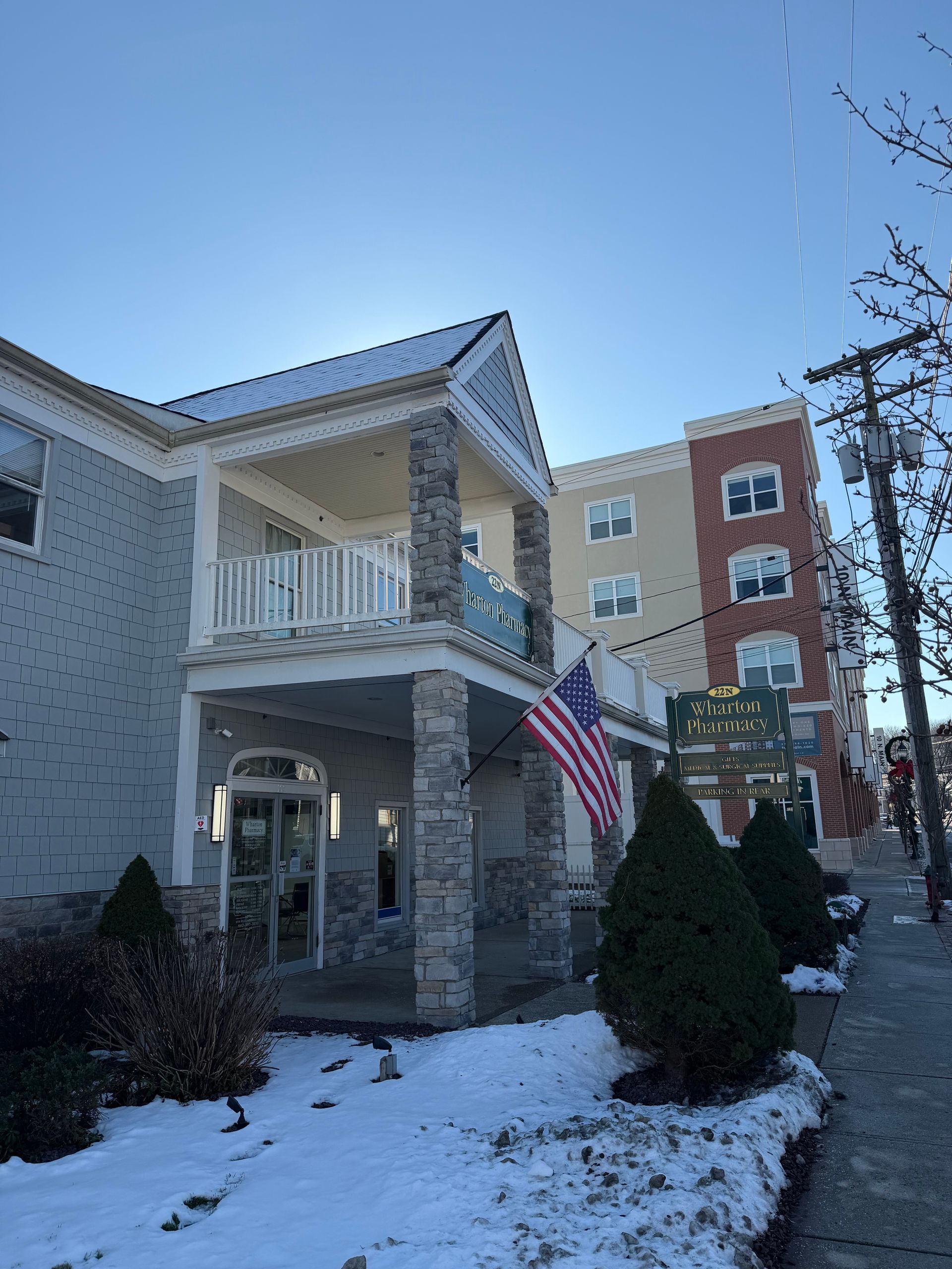 Building with stone facade and American flag; snow on the ground; sunny day.