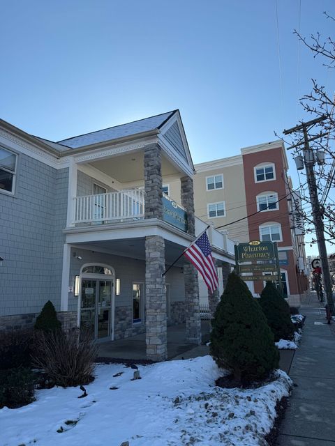 Building with stone facade and American flag; snow on the ground; sunny day.