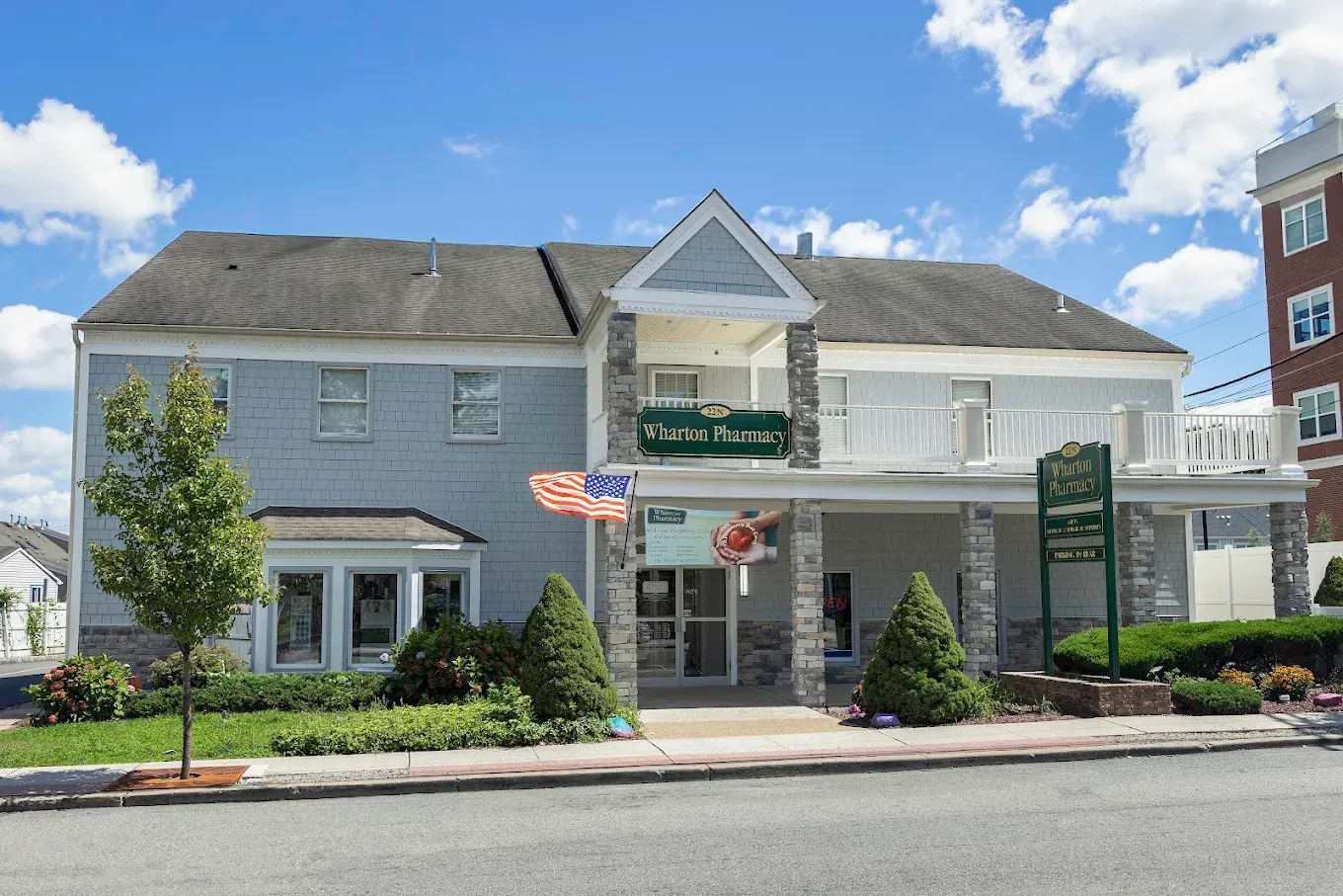 Two-story building with green sign and American flags, likely a business with a balcony.