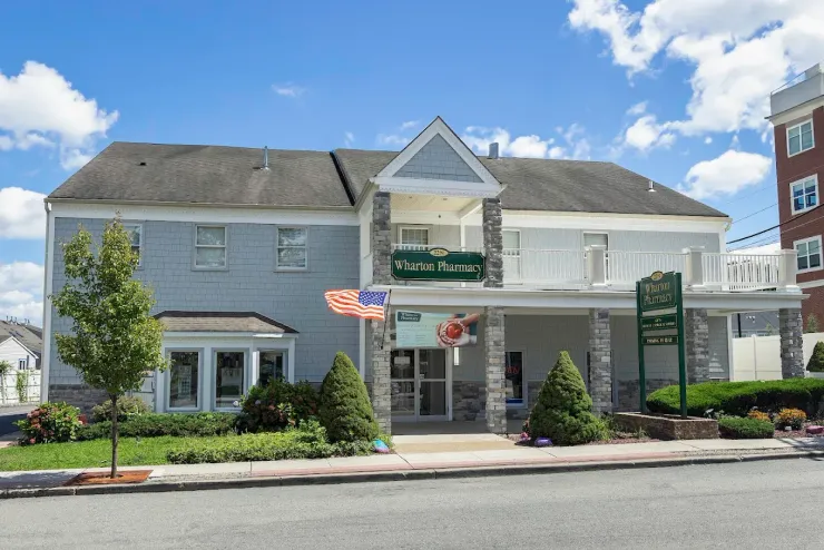 Two-story building with green sign and American flags, likely a business with a balcony.