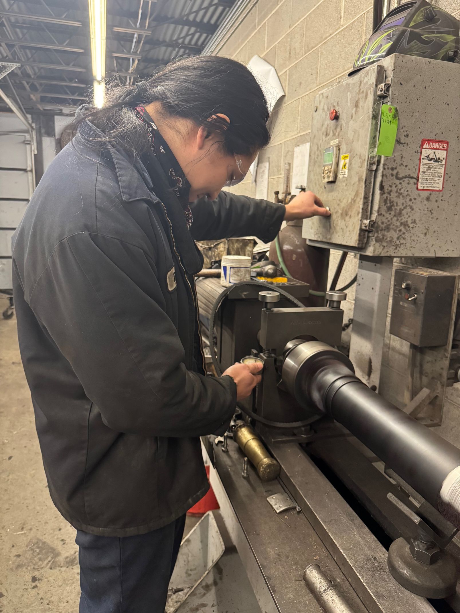 A mechanic in gloves working on a car's axle and drive shaft.
