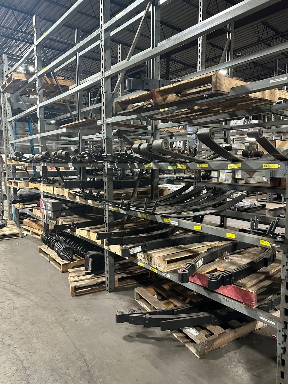 Person inspecting truck tires, writing on clipboard outdoors.