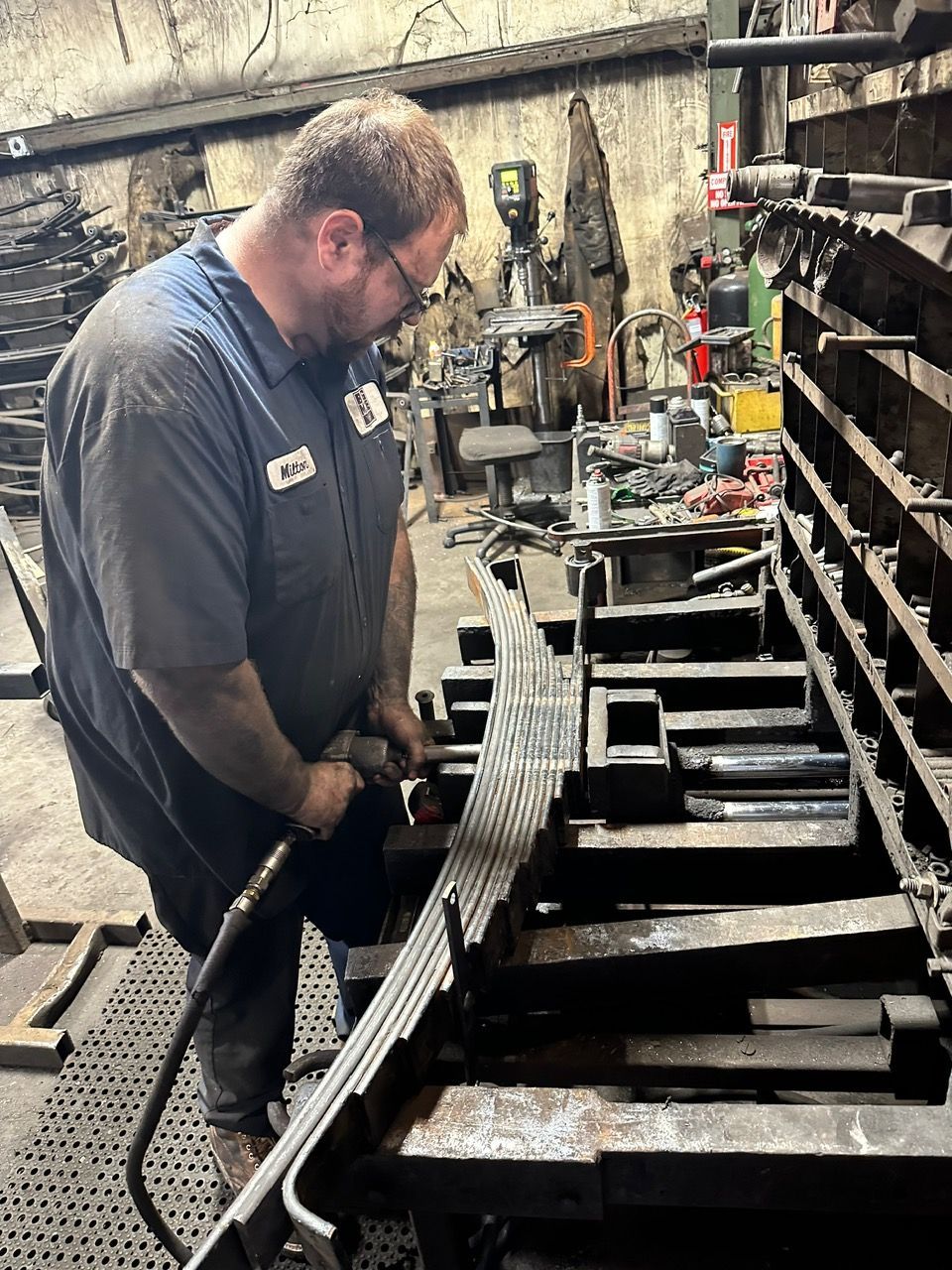 Person in work gloves inspecting a truck tire near the engine.