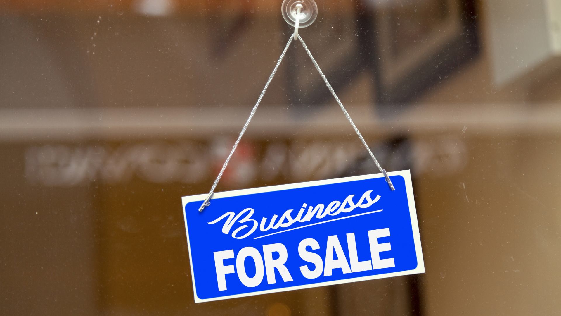 A blue business for sale sign hangs from a window