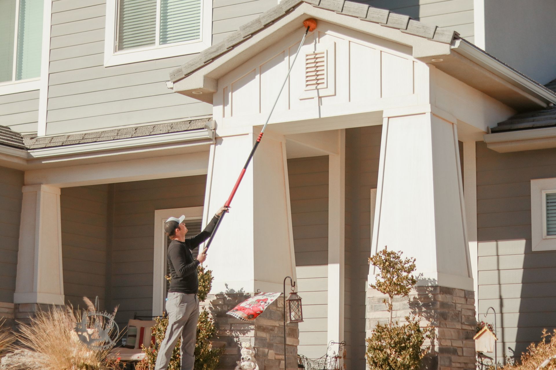 A Three Peaks Pest Control technician sweeping a home in Washington, Utah for spider webs.  