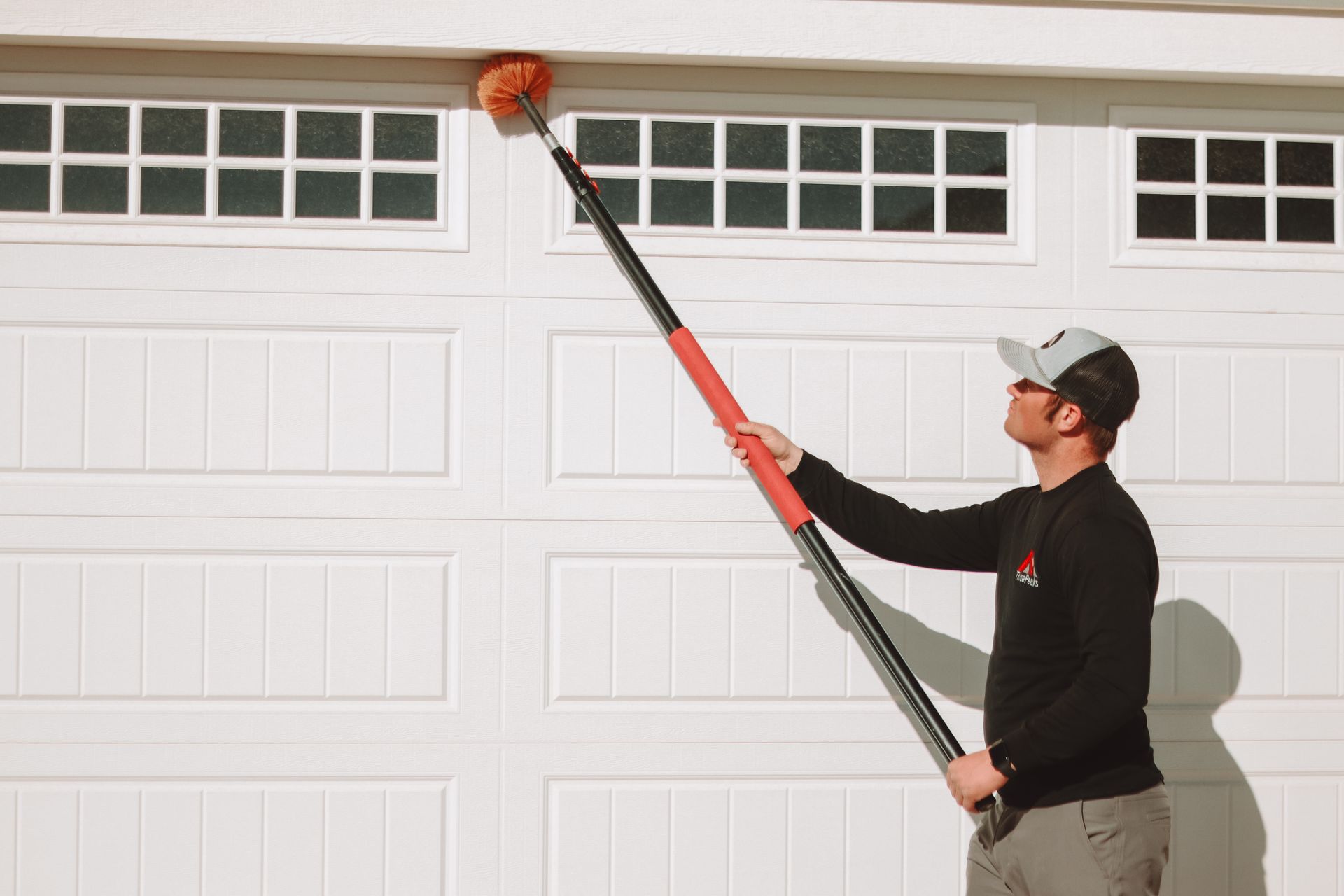 A Three Peaks Pest Control technician is sweeping a garage for spider webs in Santa Clara, Utah