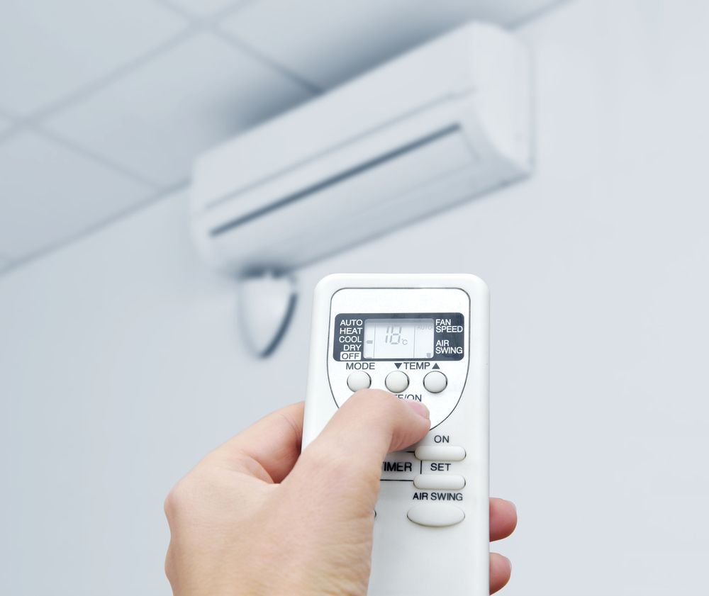 Person adjusting a split system air conditioner with remote control