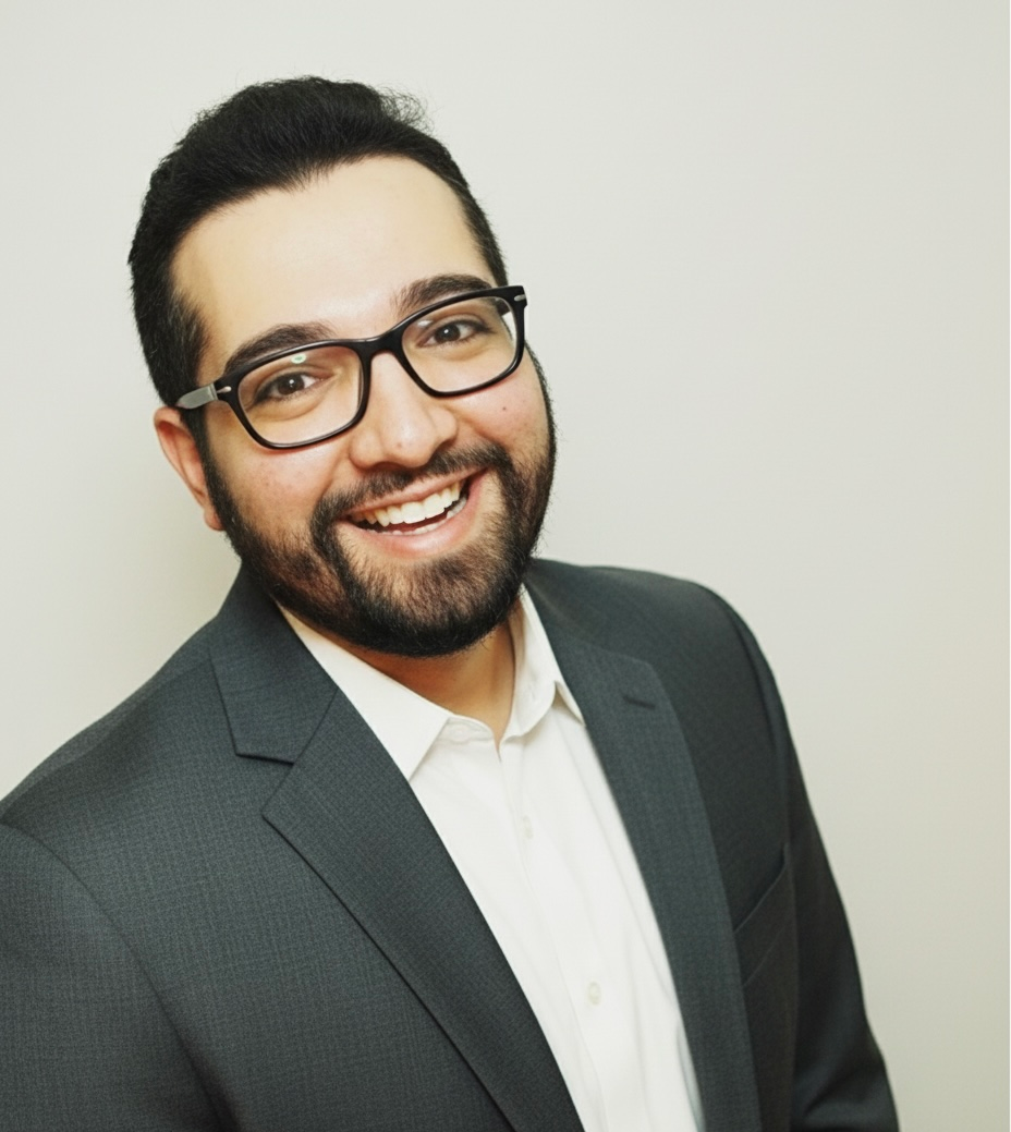 Person working at a wooden desk with a laptop, books, and plants. A vase of eucalyptus sits on a small stool.