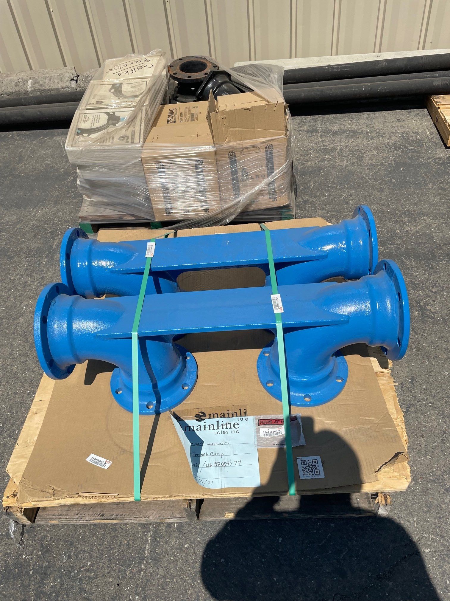 Two blue pipes are sitting on top of a cardboard pallet.