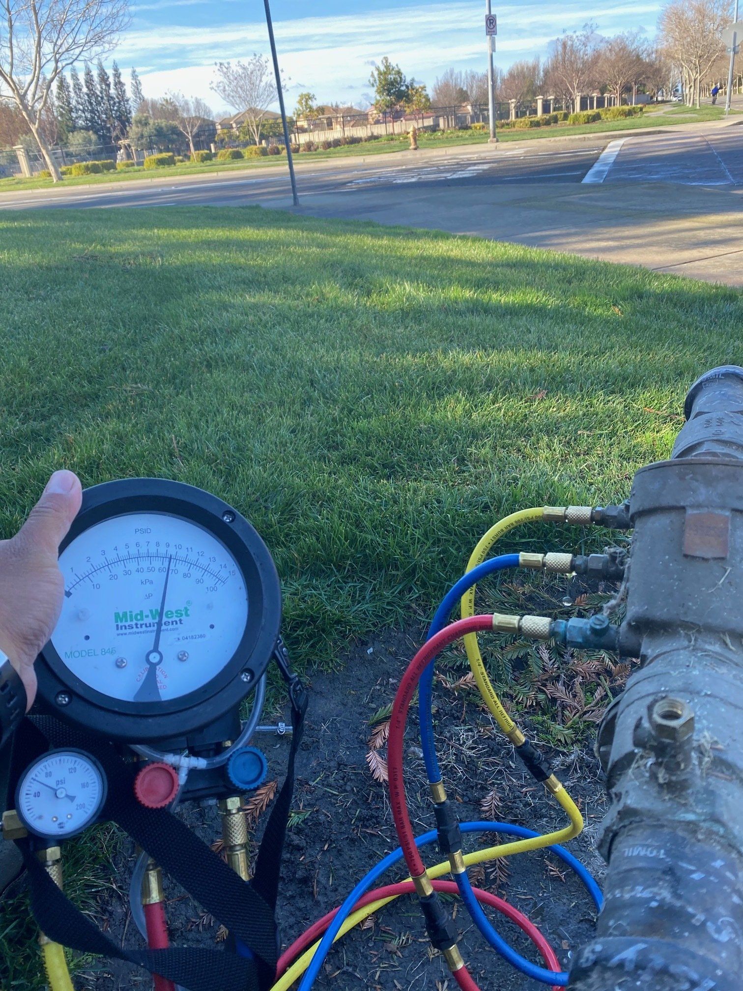 A person is holding a gauge next to a pipe.