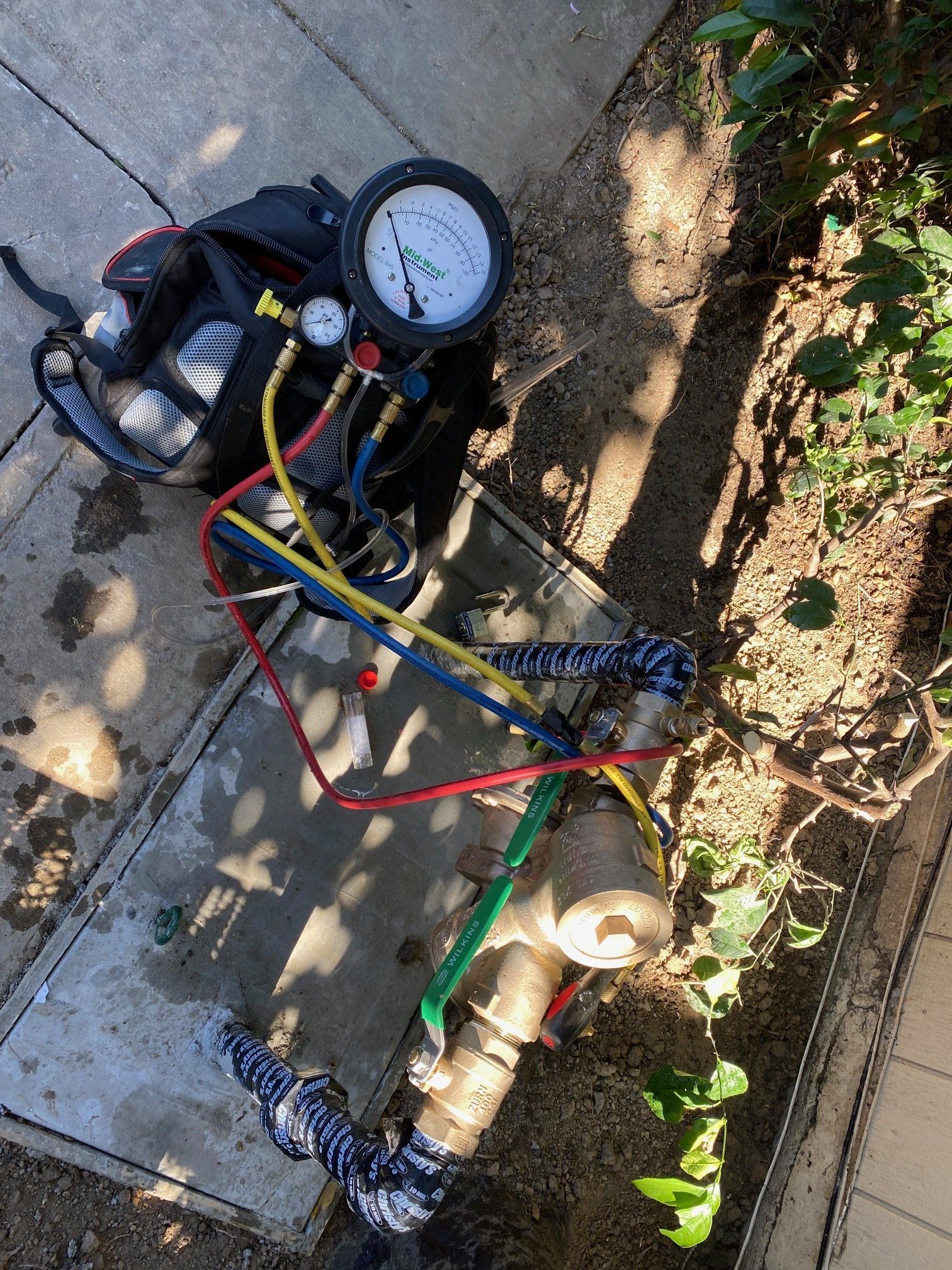 A pressure gauge is sitting on the ground next to a pipe.