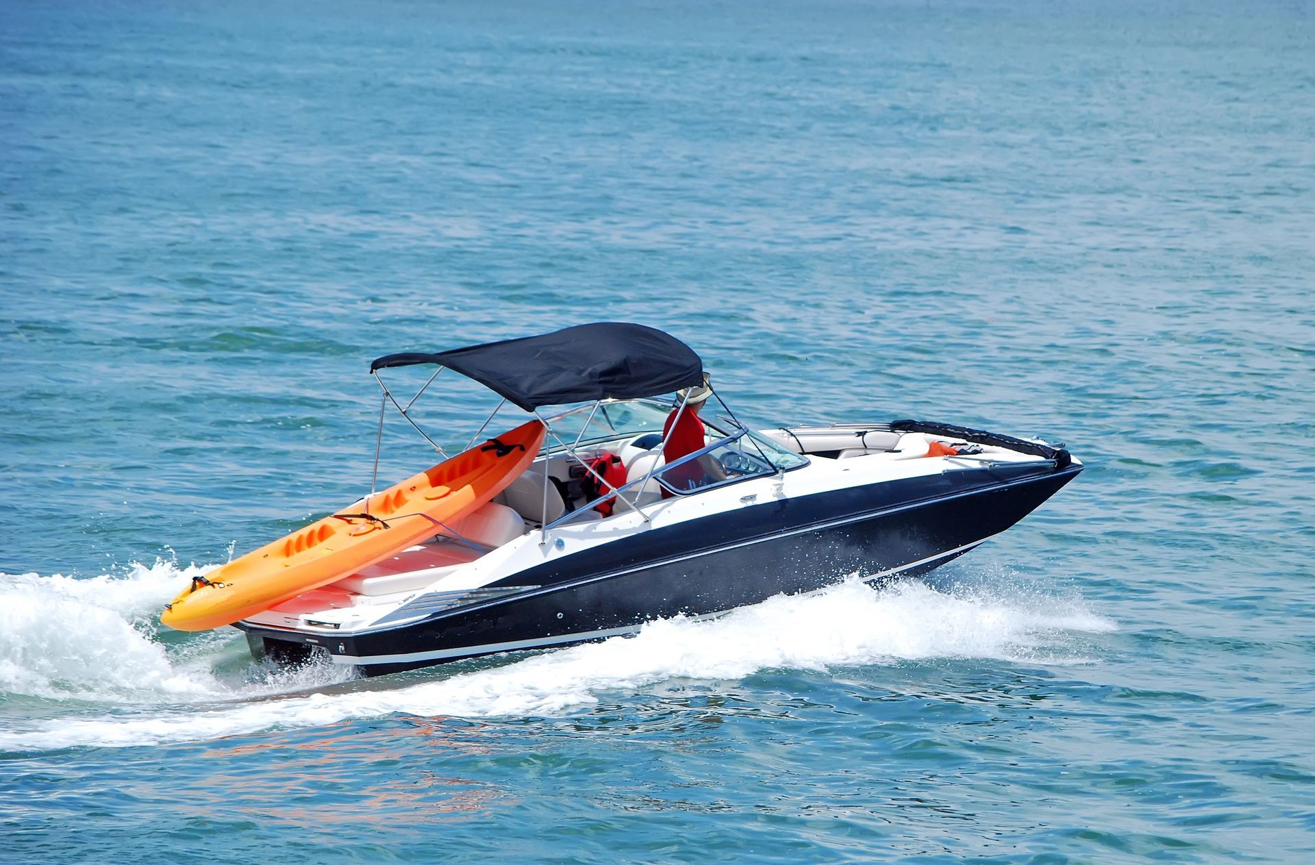 A boat with a kayak attached to it is floating on top of a body of water.