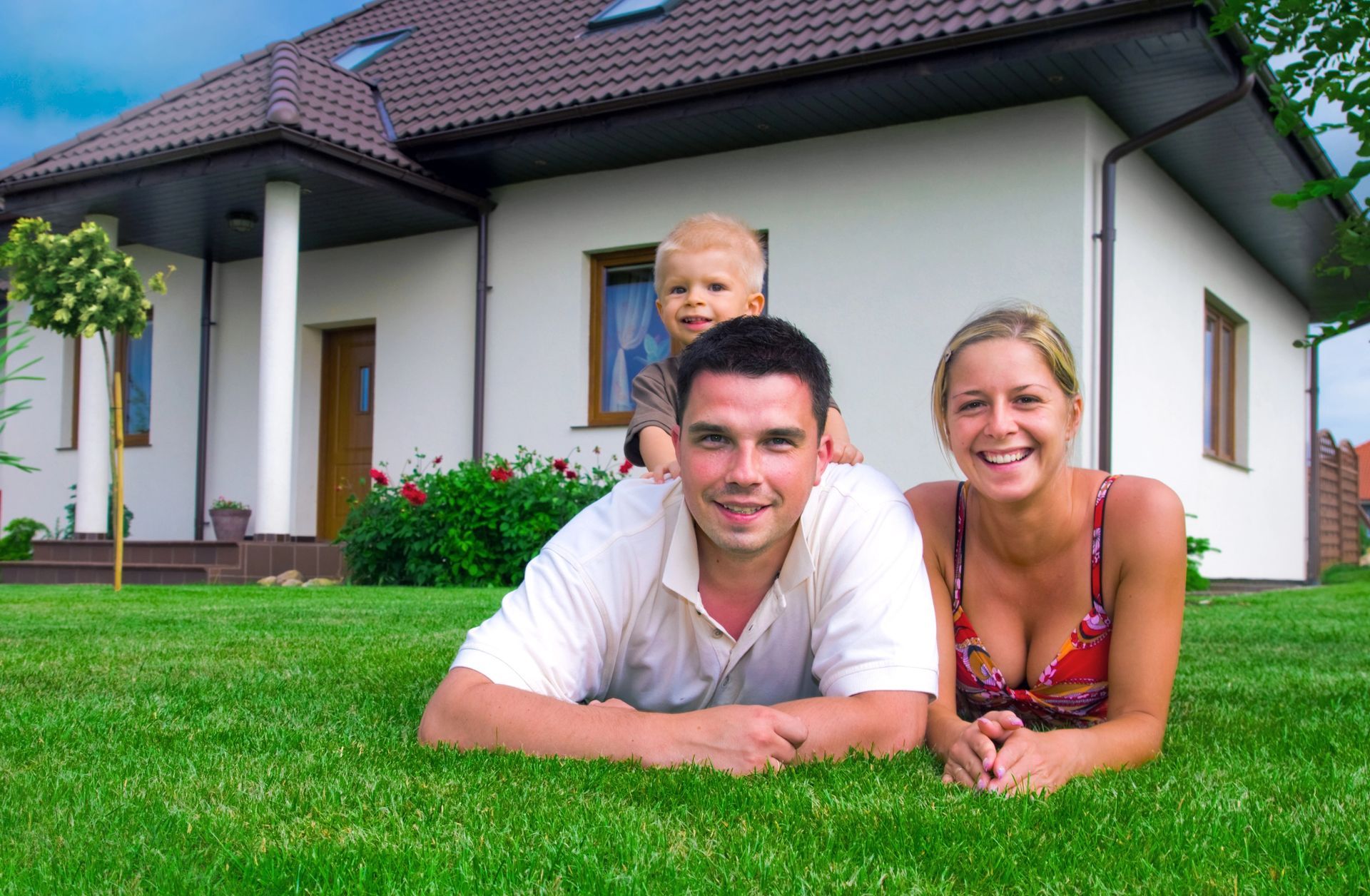 A family is laying on the grass in front of their house.