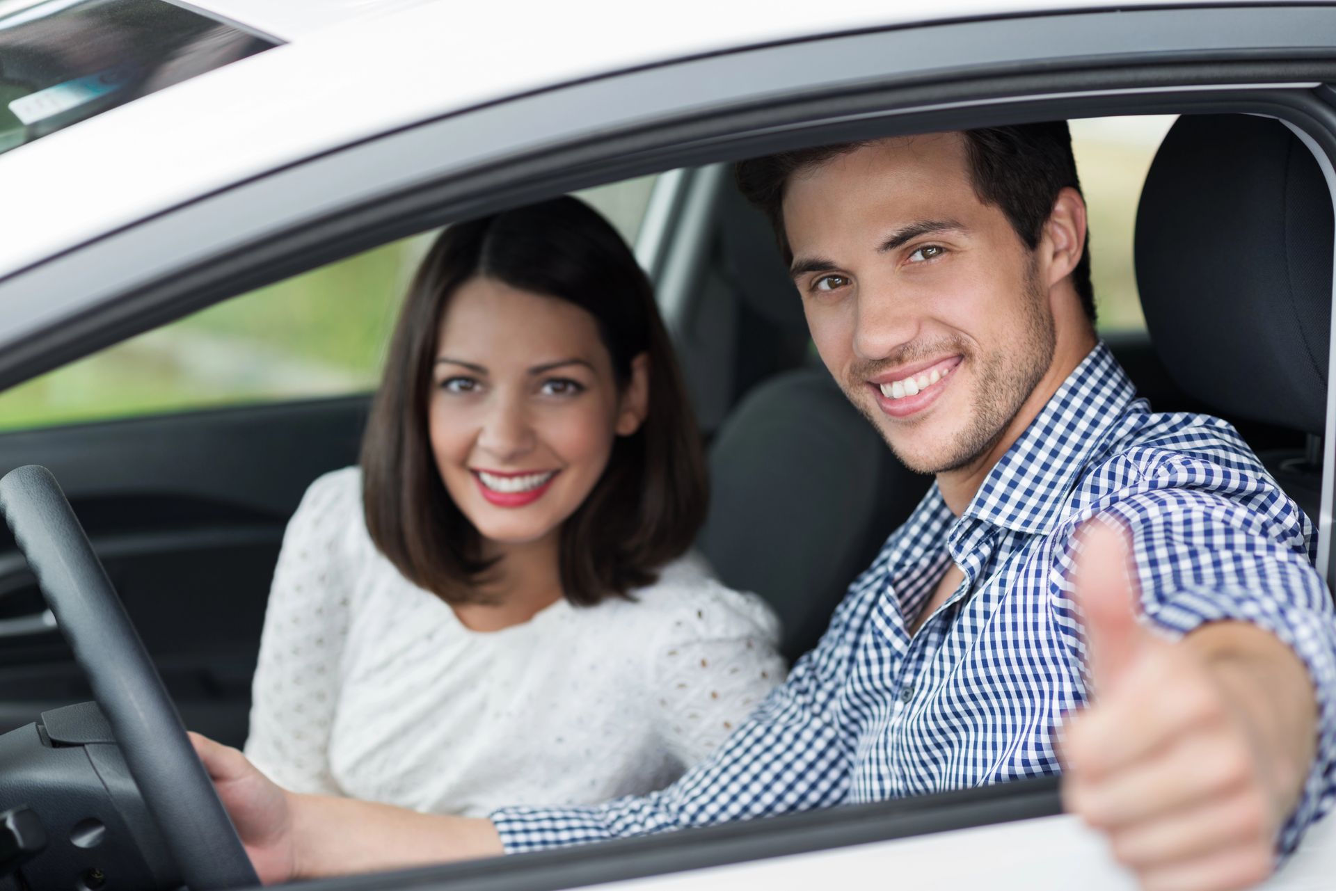two people in car giving thumbs up