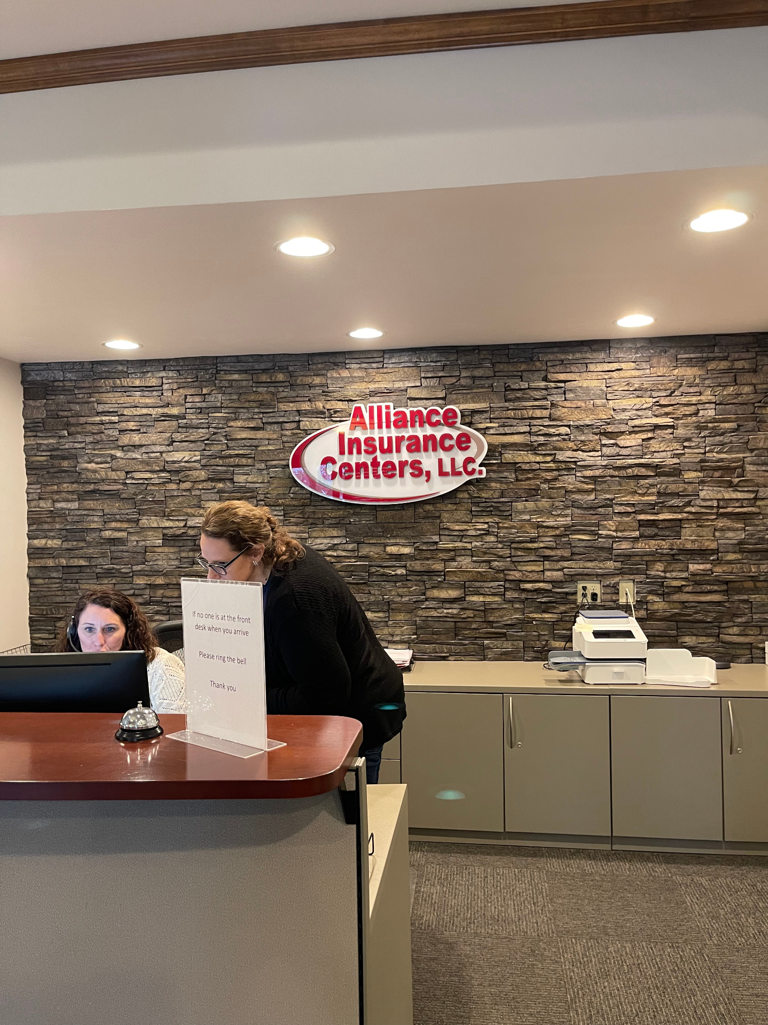 A woman is sitting at a desk in front of a sign that says insurance centers llc.