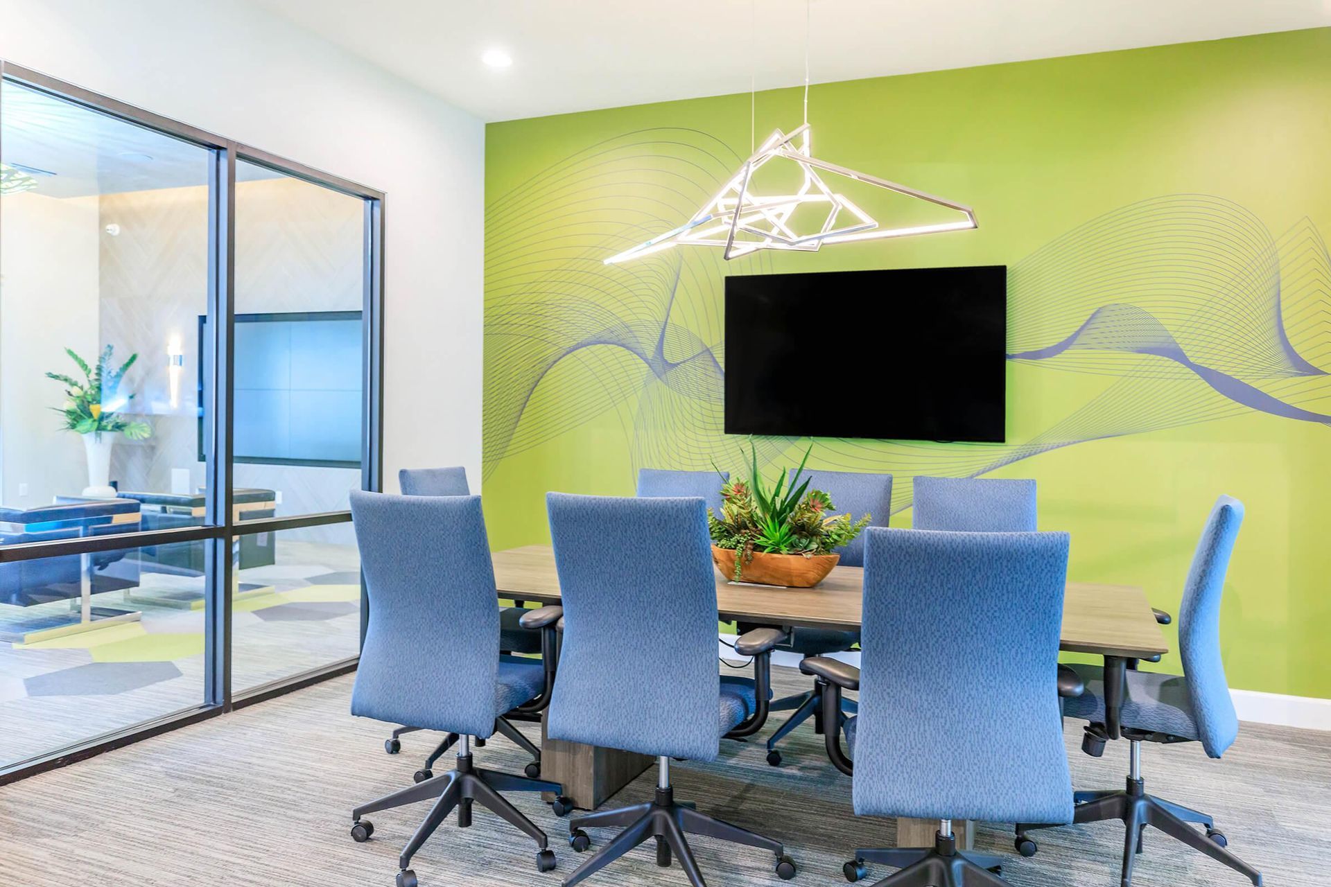 A conference room with a table and chairs and a television on the wall.