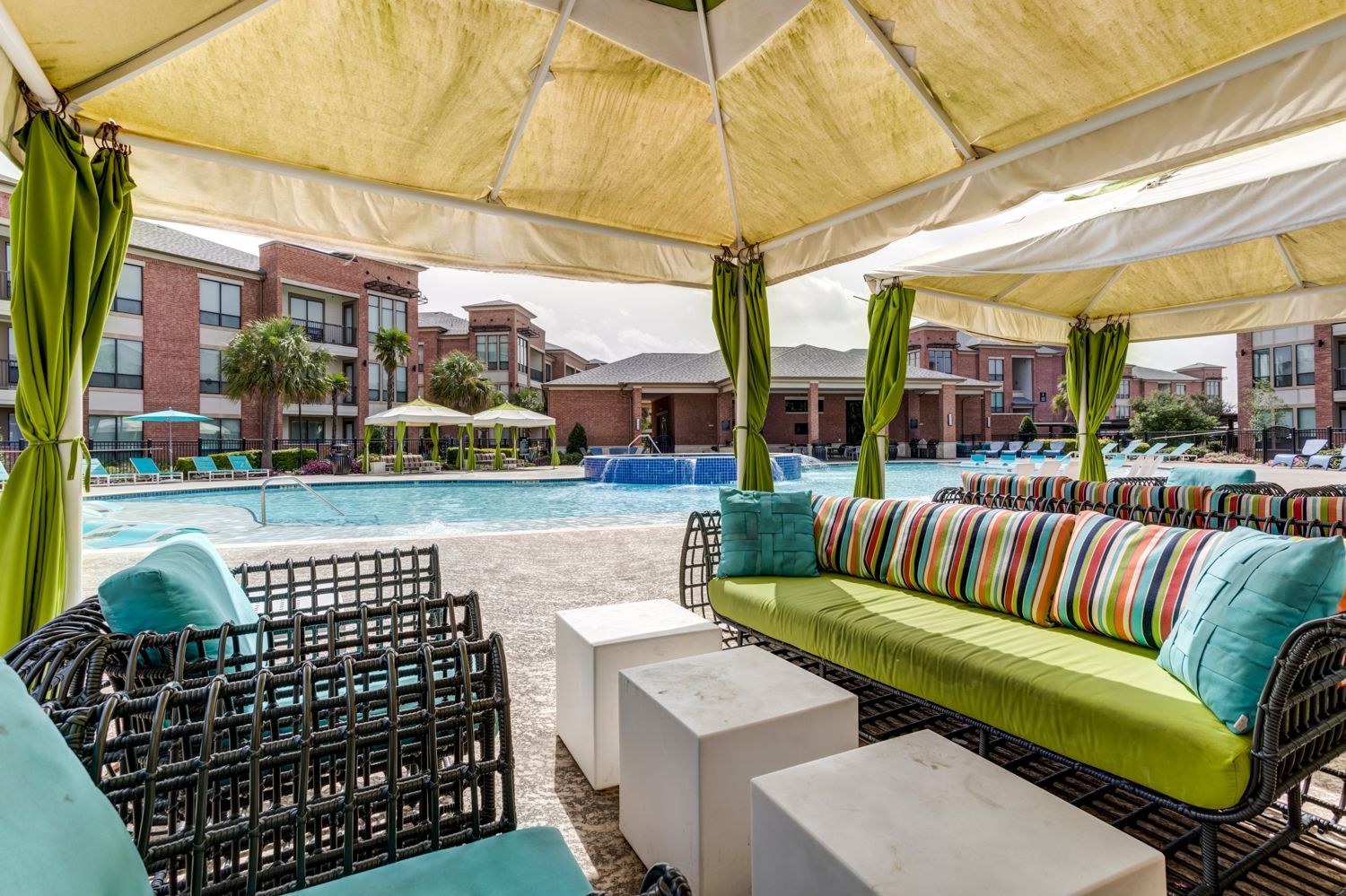 A patio area with green chairs and a swimming pool in the background.