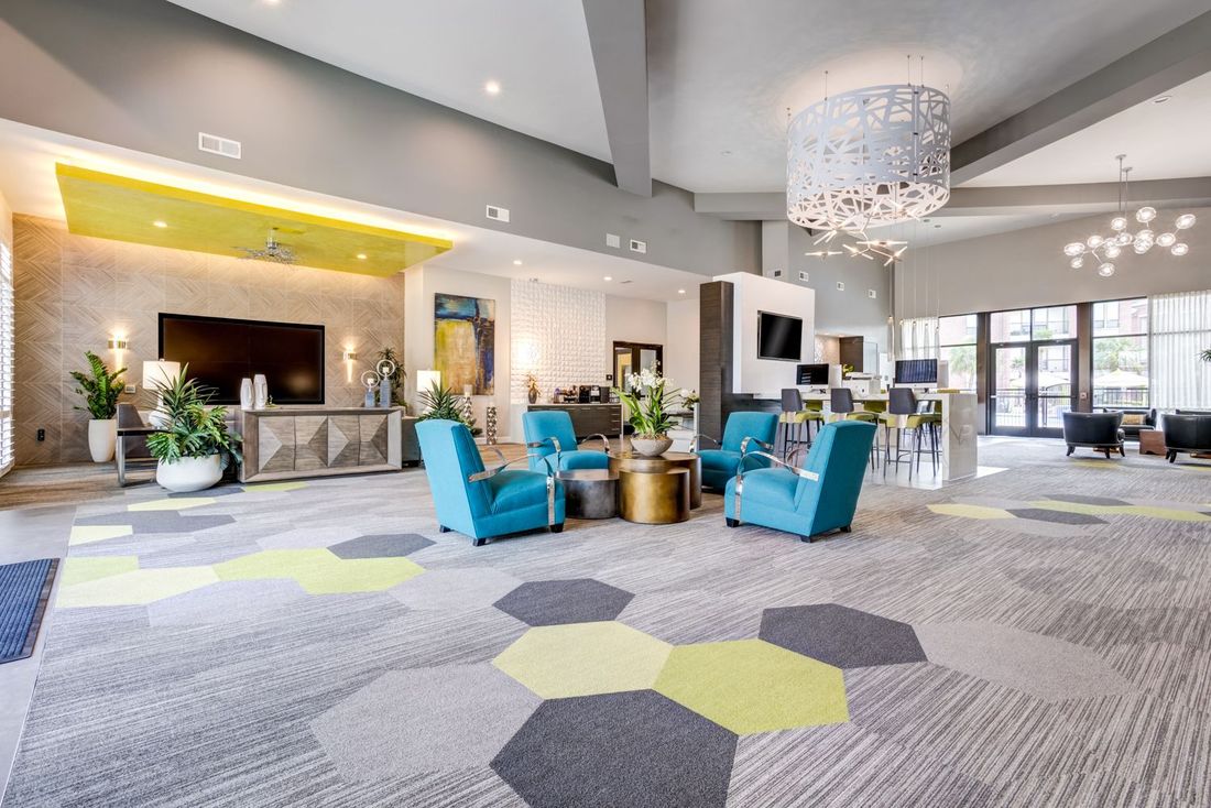 Modern lobby with teal seating, hexagon patterned rug, and large chandelier.