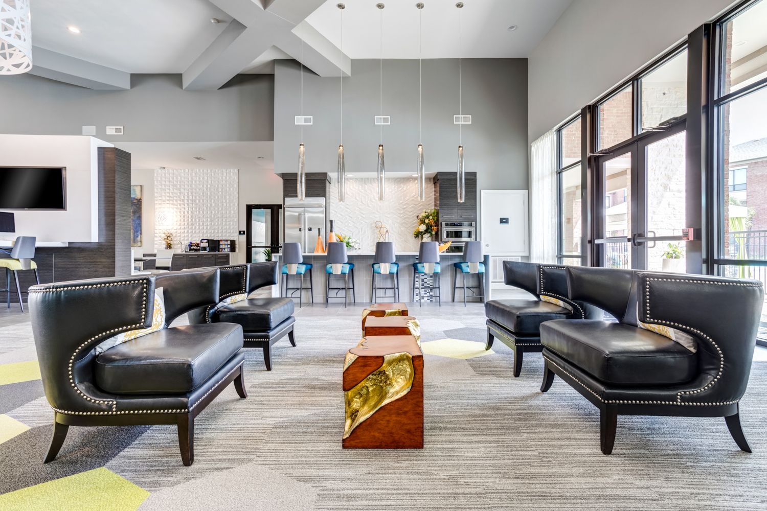 Modern lobby with black leather seating, a kitchen with barstools, and large windows.