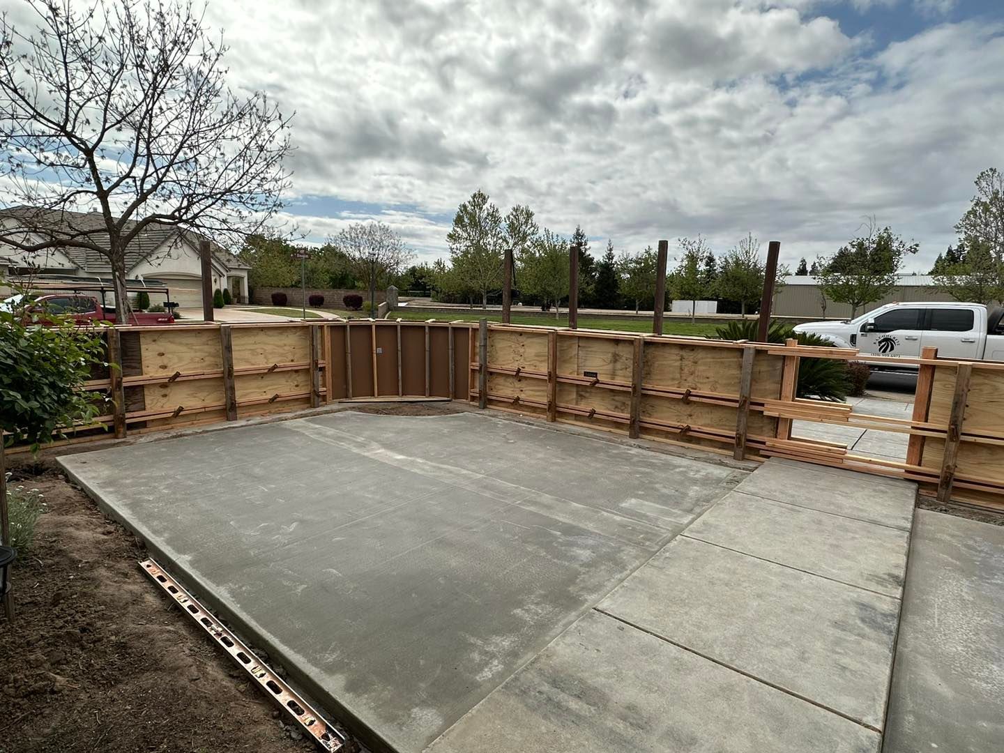 Concrete slab foundation under construction with wooden formwork and a parked truck in the background
