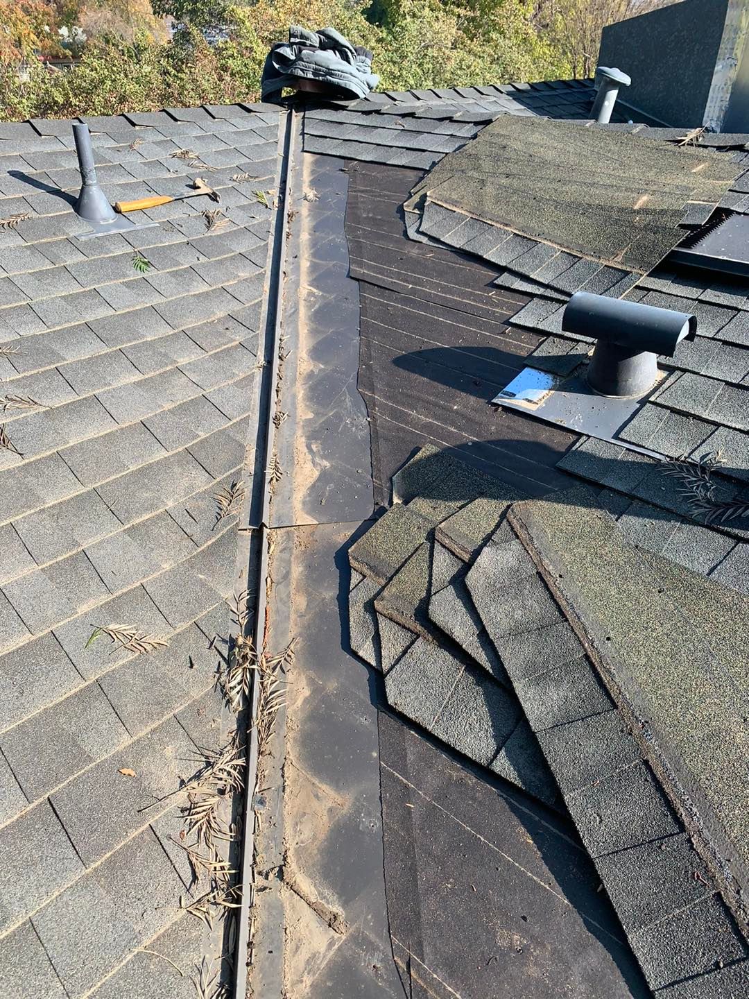 Roof ridge with shingles, worn seam, and a small vent on a dark roof
