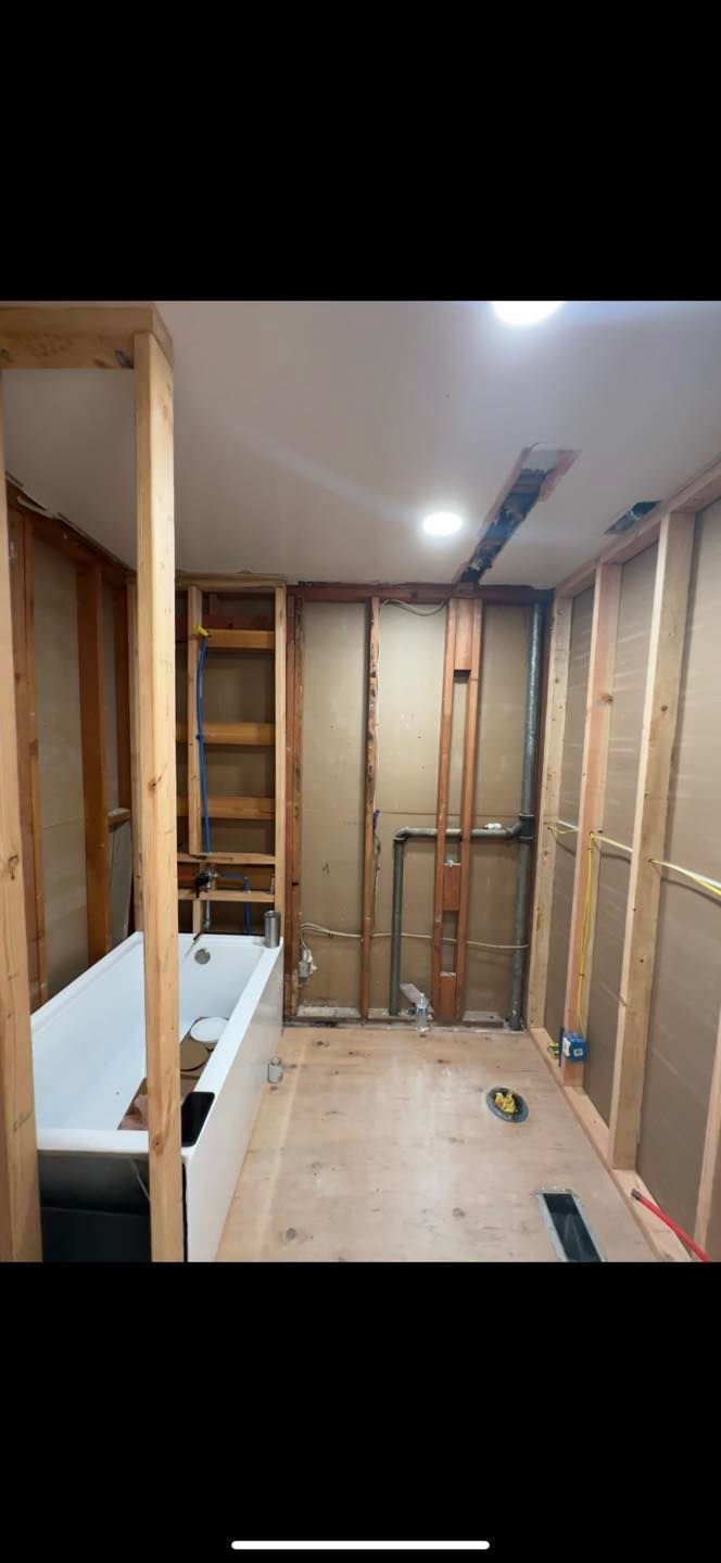 Partially finished room with exposed studs, plywood floor, and built-in bench along the left wall.