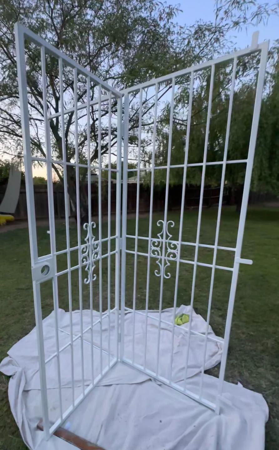 White metal outdoor pet gate enclosure on a tarp in a backyard