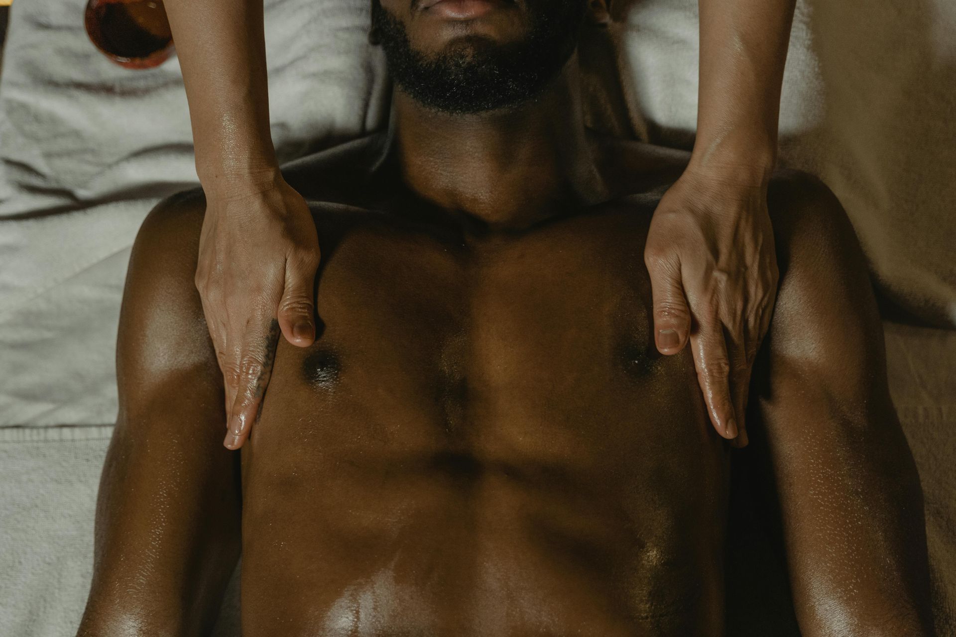 Person receiving chest massage, lying down. Hands on chest. Light skin on top, dark skin below.