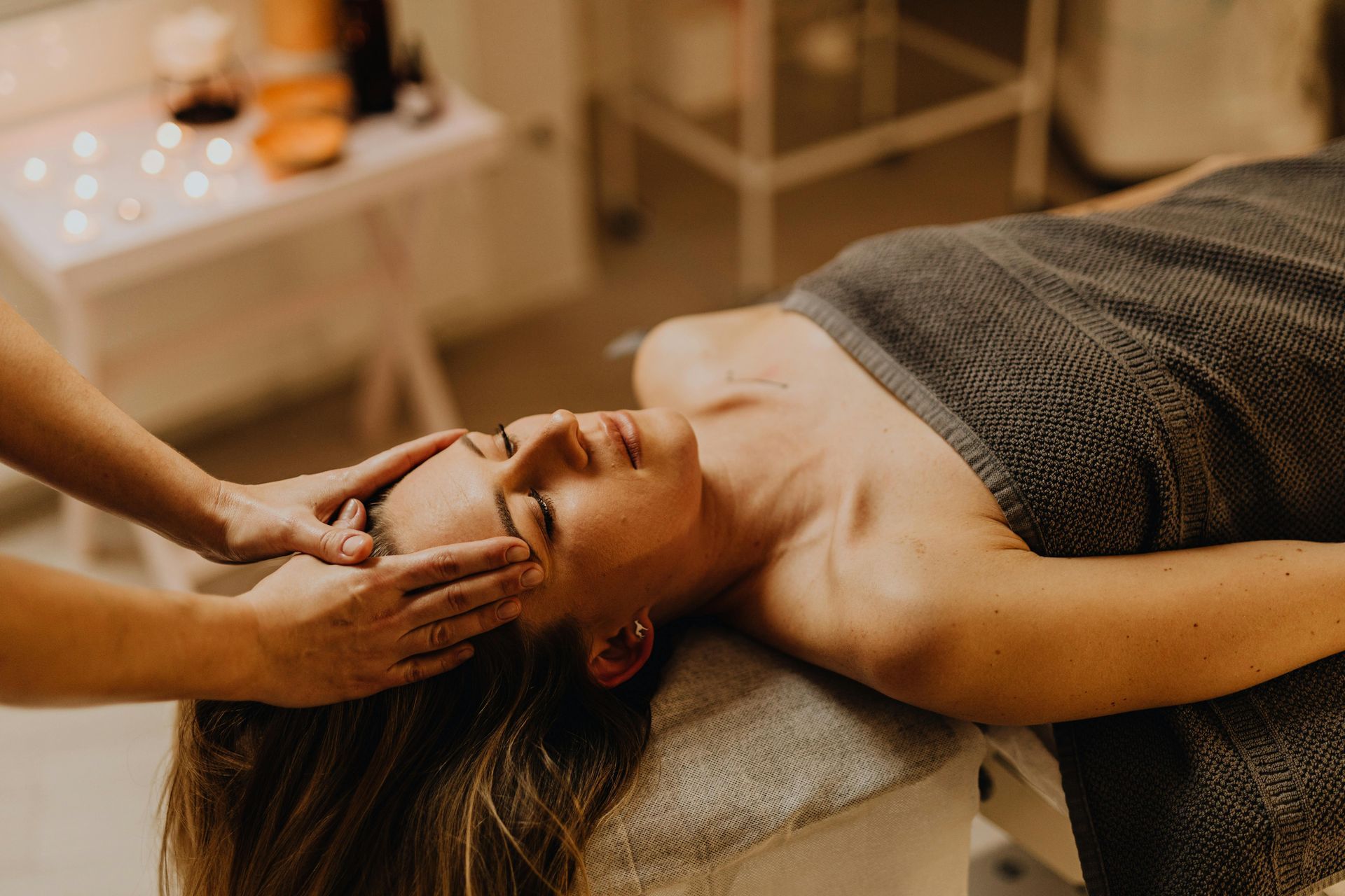 Woman receiving a facial massage on a massage table. Her eyes are closed, receiving a treatment.