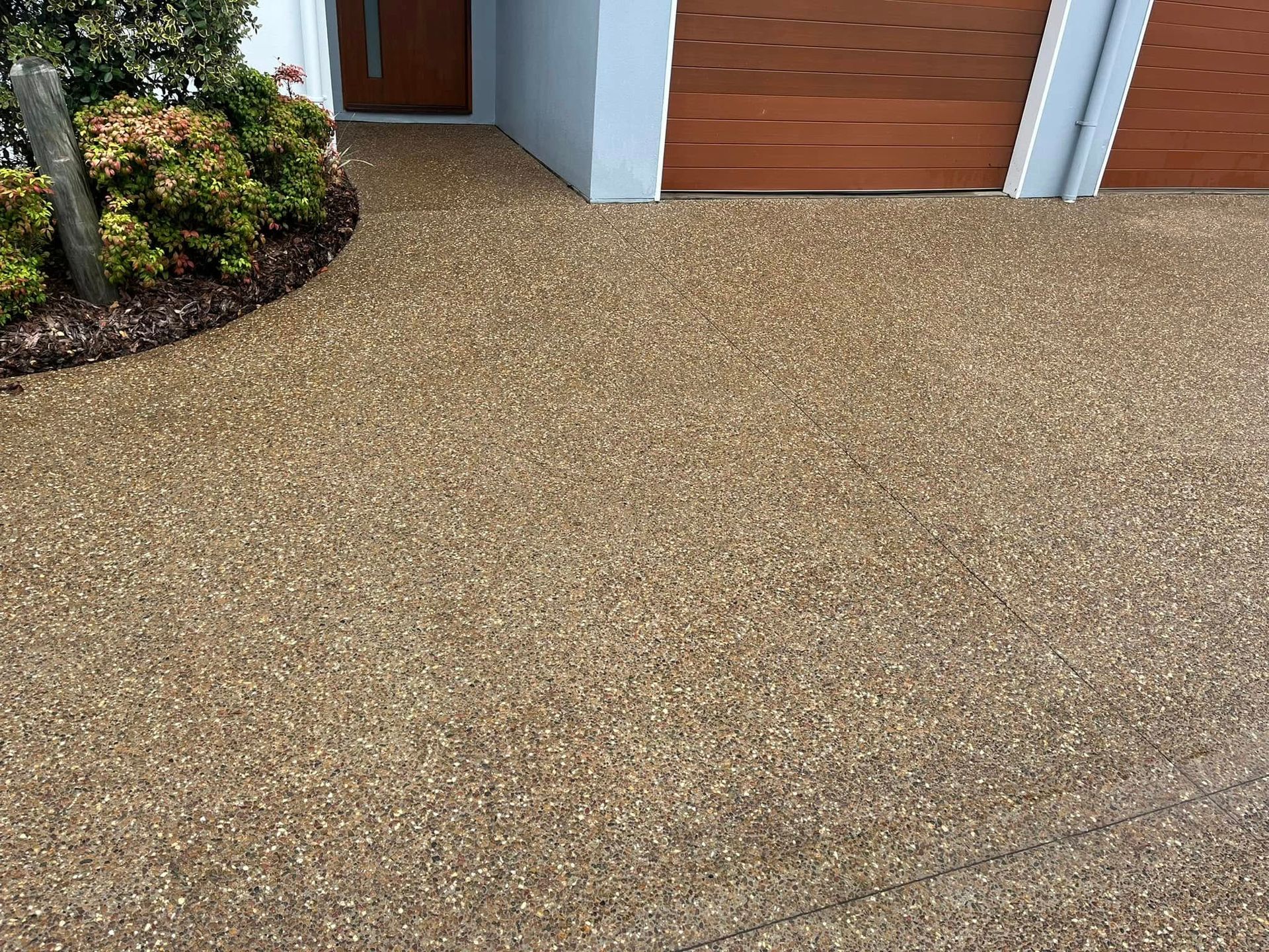 A Clean Driveway in Front of a House With a Garage Door After Cleaned by a High Pressure Water — Derek's Dirty Deeds In Maryborough, QLD