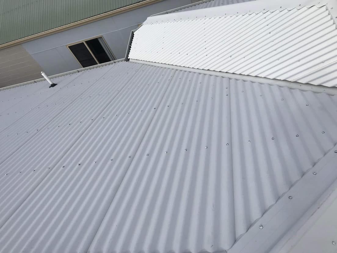 A White Corrugated Metal Roof is Sitting on Top of a Building— Derek's Dirty Deeds In Burrum Heads, QLD