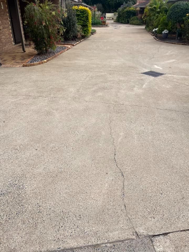 A Concrete Driveway Leading to a House With Trees on the Side of It — Derek's Dirty Deeds In Childers, QLD