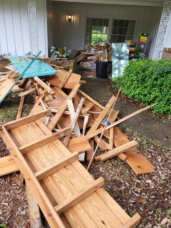 A pile of wood is sitting on the ground in front of a house.