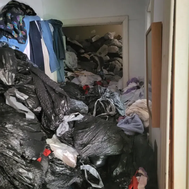 A room filled with lots of trash bags and clothes