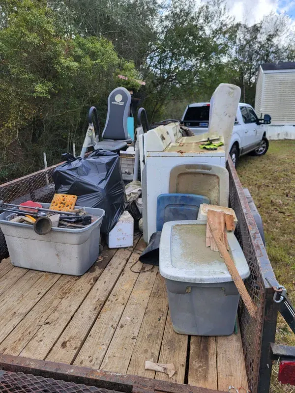 A trailer filled with lots of trash and appliances.