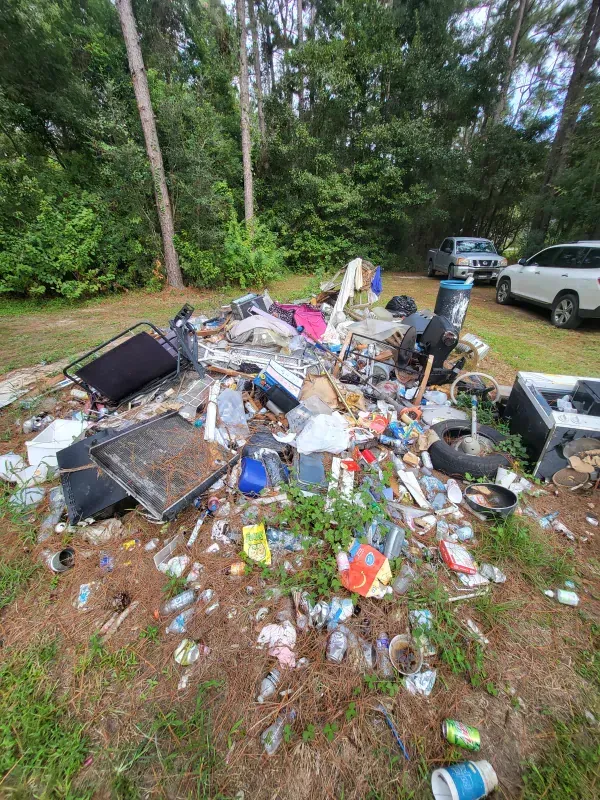 A pile of trash is sitting on top of a lush green field.
