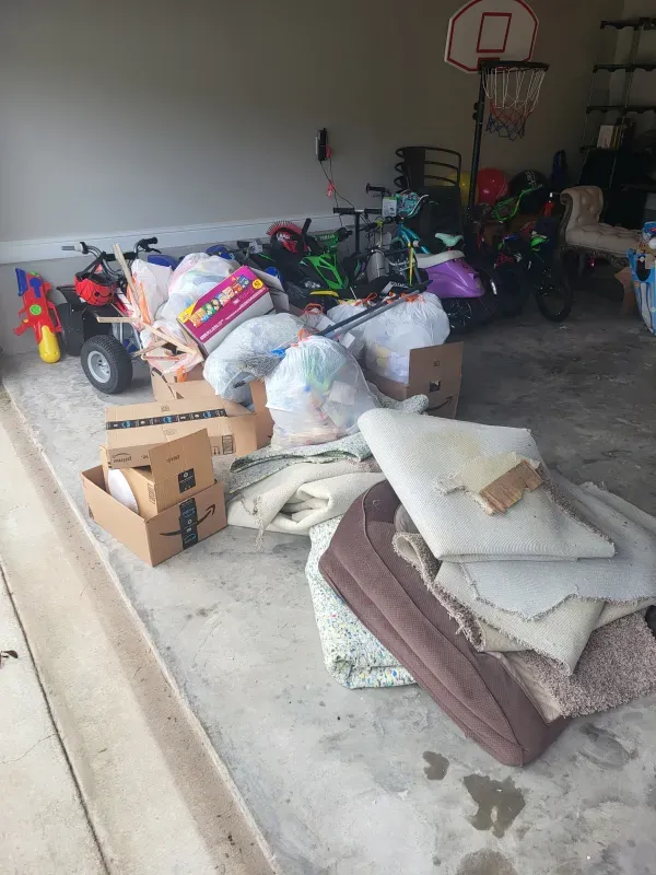 A pile of trash in a garage with a basketball hoop in the background.