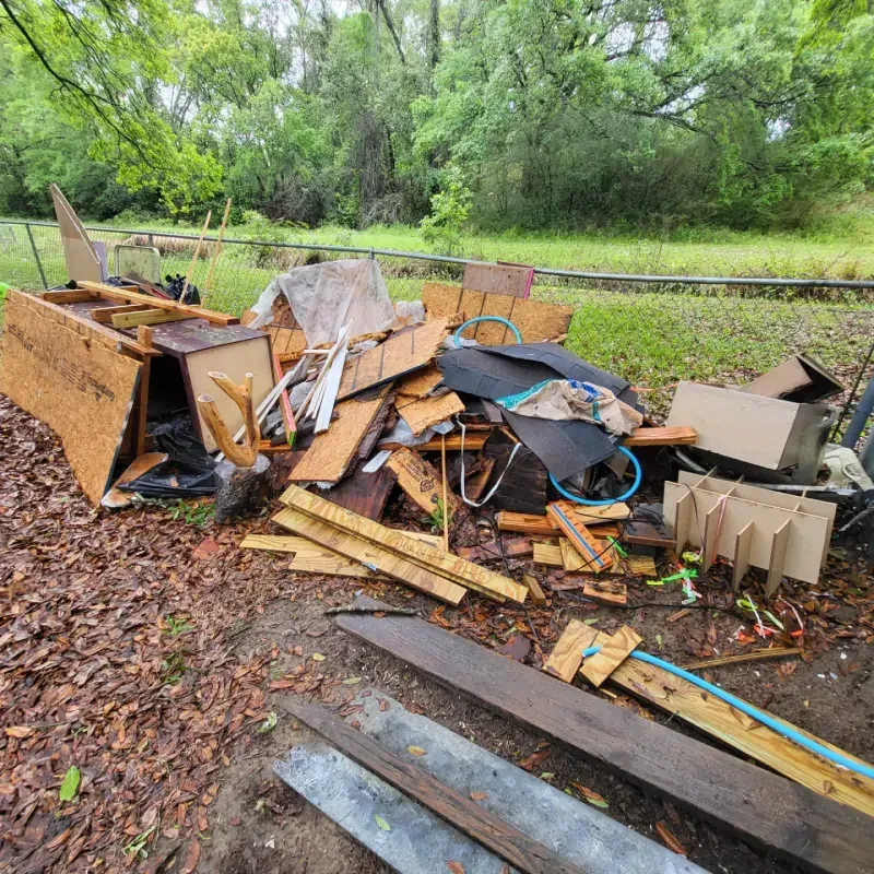 A pile of wood is sitting on the ground in a field.