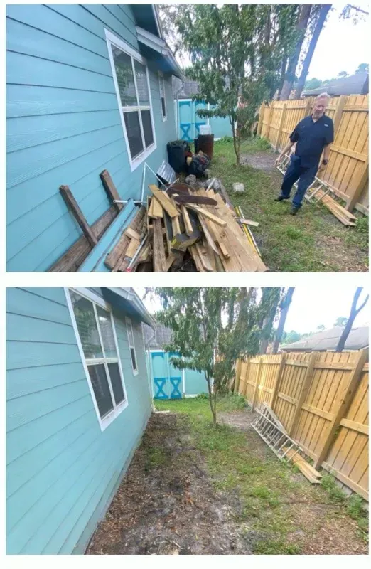 A man is standing next to a pile of wood in front of a house.