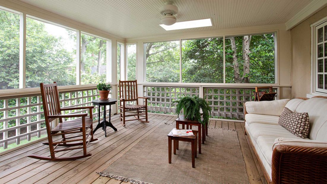 A screened in porch with rocking chairs and a couch