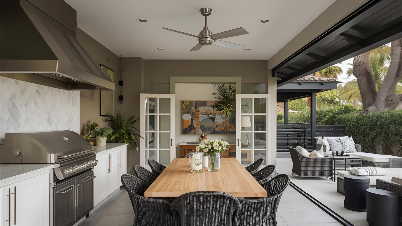 Outdoor kitchen and dining area with stainless steel grill, wooden table, and wicker chairs.